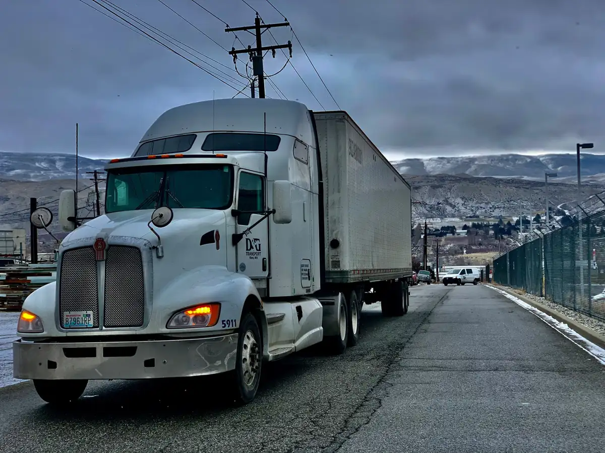 D&G Transport Kenworth with a dry van on a road with snow-dusted hills behind