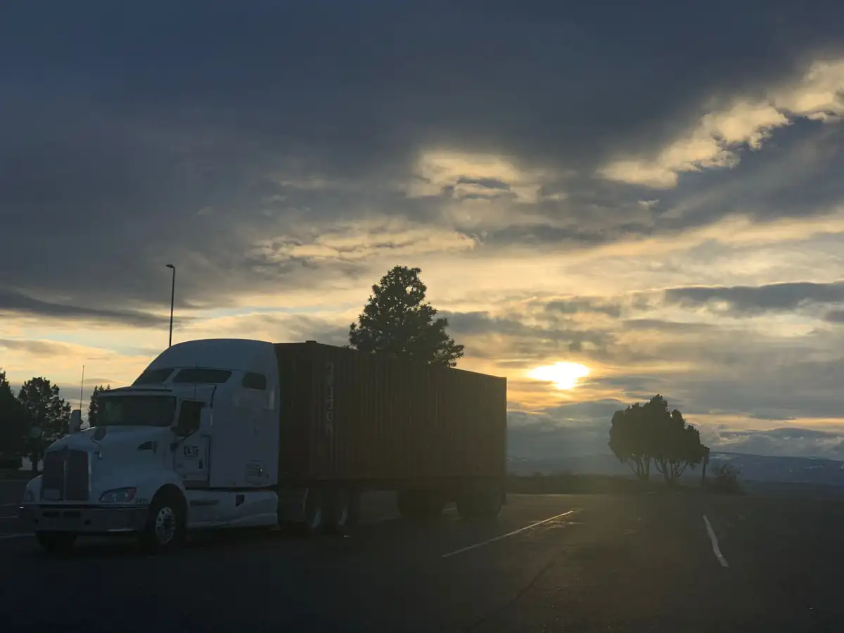 D&G Transport tractor with an ocean container parked at sunset