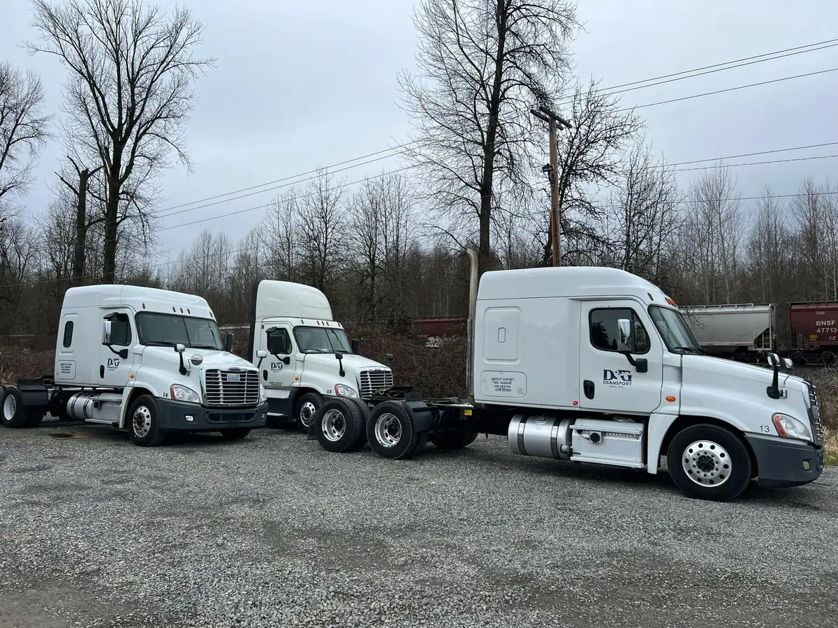 D&G Transport tractors staged railside on a gravel lot in the Pacific Northwest