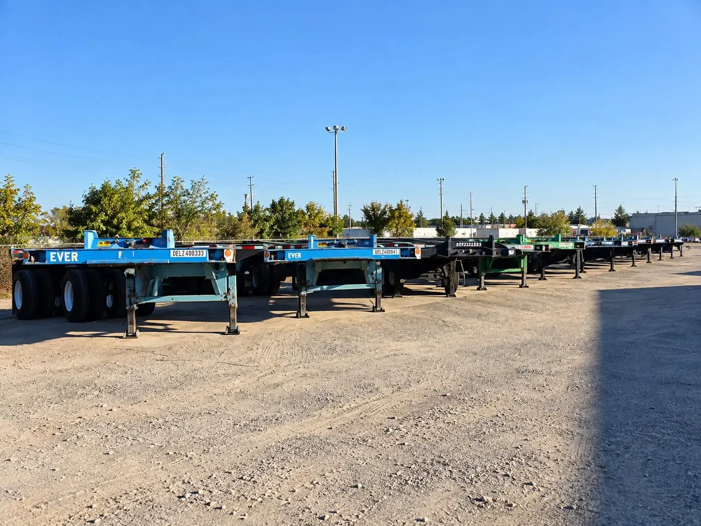 Row of empty blue and green container chassis parked in the D&G Transport yard