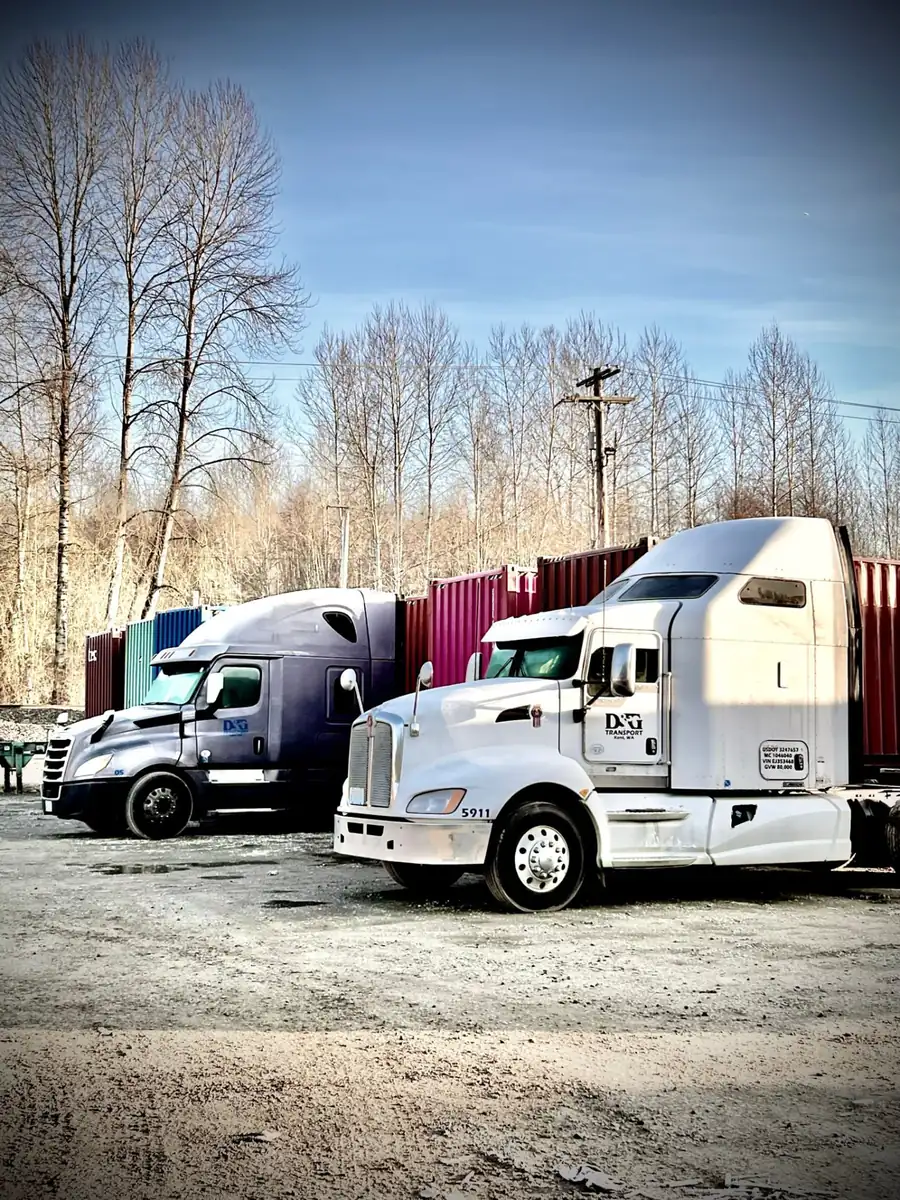 D&G Transport tractors parked in front of a wall of ocean containers