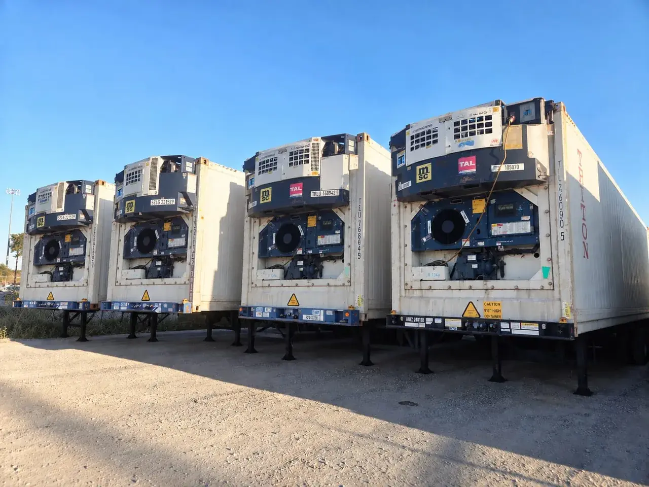 Row of refrigerated reefer containers on chassis with their refrigeration units visible